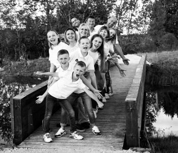 Photo de famille, debout sur un pont au-dessus d'un étang, les bras en l'air.