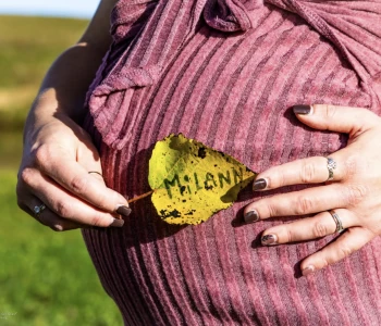 Femme enceinte tenant une feuille avec le prénom Milann inscrit dessus