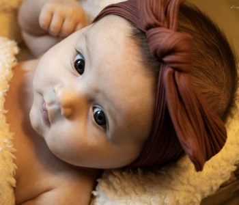 Bébé aux yeux grands ouverts portant un bandeau brun