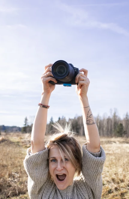 Photographe en extérieur tenant son appareil photo dans un champ