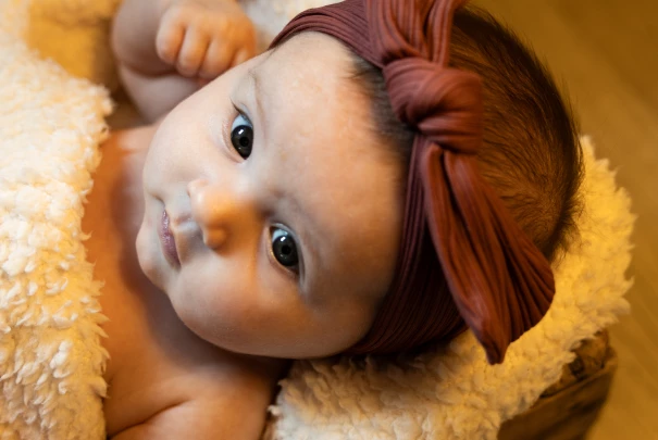 Bébé allongé sur un plaid douillet avec un bandeau noué brun